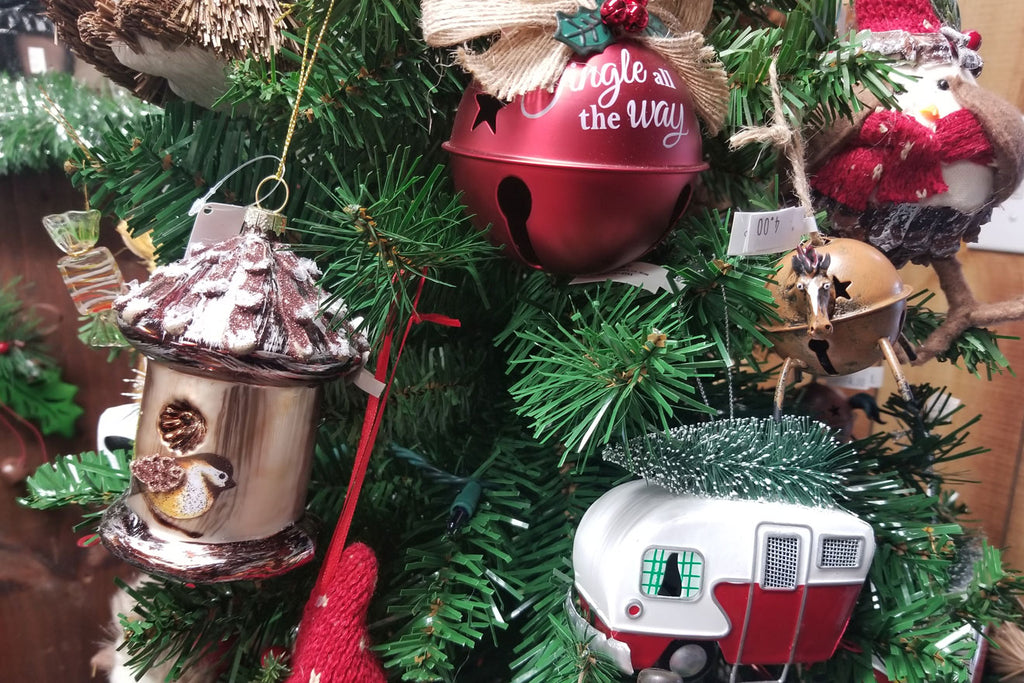 Christmas ornament of a bird feeder, holiday bell, and Rv on a christmas tree